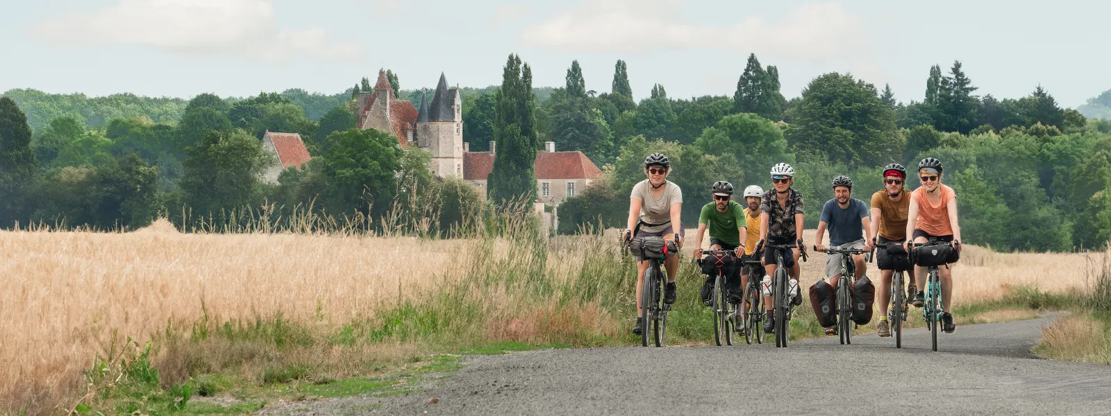 Cyclistes roulant sur une route avec vue du manoir de la VĂŽve en arriĂšre-plan
